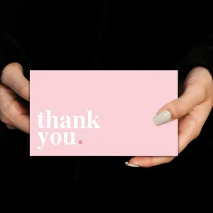 Pink thank you card held by hands against a black background for wedding and gifts