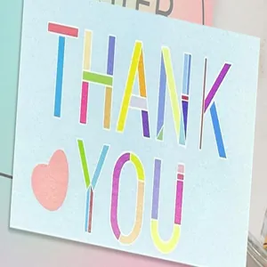 Detail view of a colorful "THANK YOU" greeting card with a cute heart on light blue paper
