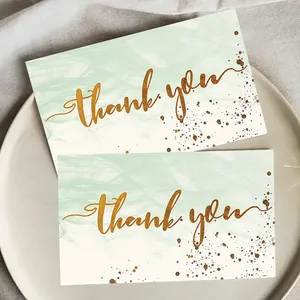 Close-up of elegant marble pattern thank you cards featuring golden cursive calligraphy