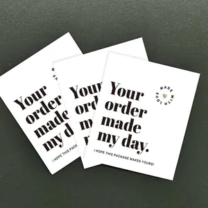 Close-up of minimalist white business thank you cards with gold heart logo