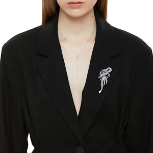 Elegant silver bow brooch with blue crystals shown on a black blazer detail view
