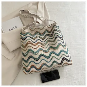 Detailed view of the large knit tote bag with a vibrant wave pattern and wide strap