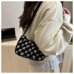 Close-up of a checkered canvas underarm bag worn over the shoulder for a casual look.