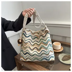 Detailed view of a knitted hobo bag with colorful wave patterns and patterned wide strap