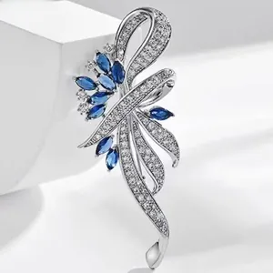 Detail view of an elegant silver-tone brooch with blue and clear pavé crystal accents.