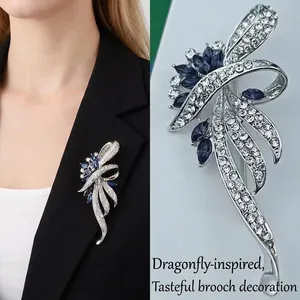 Elegant blue dragonfly brooch with shimmering crystals shown on a black blazer and in detail