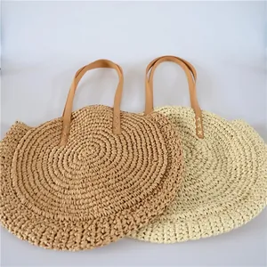 Detail view of round straw beach bags in beige and light brown with leather straps