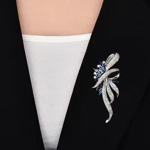 Detailed view of an elegant silver brooch with blue crystals worn on a black suit jacket