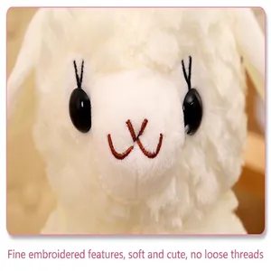Close-up of a white plush sheep toy with delicate embroidered facial features.
