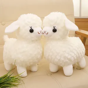 Two adorable white alpaca plush toys with diamond textured fur on a beige sofa