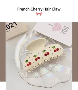 Close-up of elegant cream acetate hair claw clip with cherry rhinestone detail