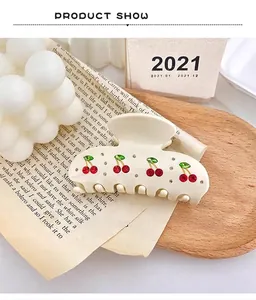 Close-up of elegant cream acetate hair claw clip with sparkly rhinestone cherry design