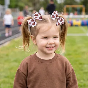 Petite fille portant des nœuds pour cheveux motif football sur un terrain de sport