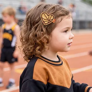Détail d'une pince à cheveux basket en forme de cœur pailleté portée par une petite fille