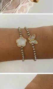 Détail de bracelets papillon et fleur dorés avec incrustation de nacre et strass.