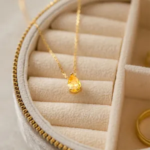 Détail raffiné d'un collier en zircon jaune en forme de poire dans son écrin