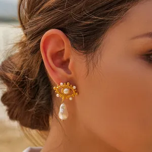 Close-up detail of French vintage evil eye gold earrings with pearls on model's ear