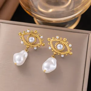 Macro detail of vintage golden Evil Eye earrings with Baroque pearl drops.
