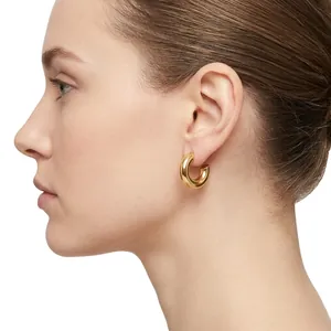Elegant gold-plated stainless steel hollow tube hoop earrings worn by a model
