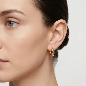 Detailed close-up view of stylish chunky gold hollow tube hoop earrings worn on ear
