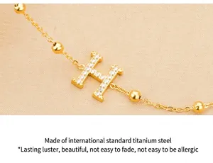 Detailed view of gold titanium steel bracelet with zircon inlaid letter H pendant
