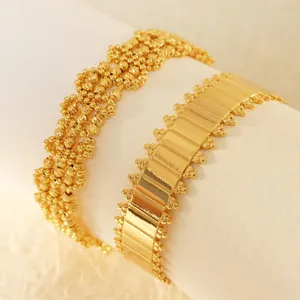 Detailed view of two gold plated hollow geometric mesh bracelets on a white stand.