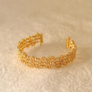 Detailed macro shot of a golden hollow geometric grid cuff bracelet with beaded texture