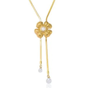 Detail of gold flower tassel necklace with elegant faux pearl pendants on white back.