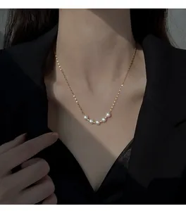 Detailed close-up of an elegant white pearl smile necklace worn by a female model