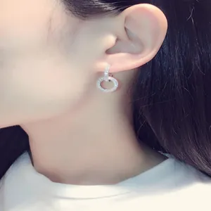 Detailed side view of sparkling micro-paved double hoop silver earrings on model