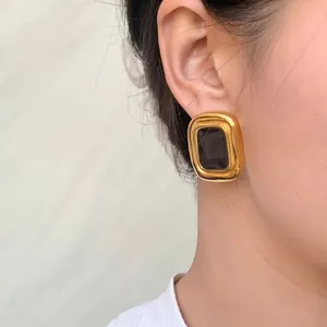 Macro detail of a vintage gold-plated stainless steel earring featuring a black stone