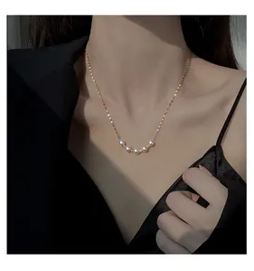 Close-up detail of a delicate gold necklace featuring five elegant white pearls.