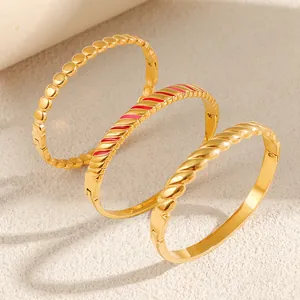 Detailed view of three gold titanium steel bangles with beaded, enamel, and twisted designs.