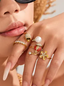 Detailed close-up view of a gold ring set featuring bell, ladybug, and flower designs
