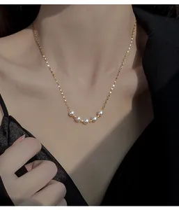 Close-up of an elegant smile pearl necklace featuring five white pearls on a gold chain.