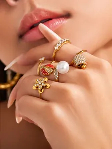 Macro detail of fashionable gold-plated ladybug and bell rings with sparkling zircons set