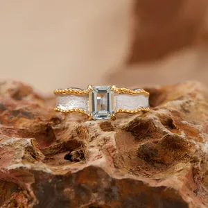 Macro view of a textured matte sterling silver ring with an emerald-cut gemstone