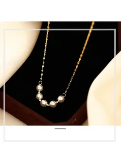 Macro view of an elegant gold smile necklace featuring five lustrous white pearls