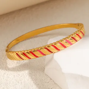 Detail of a titanium steel bracelet with red and pink enamel stripes on gold.
