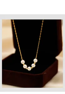 Detailed close-up of a smile pearl necklace featuring five white pearls on a gold chain
