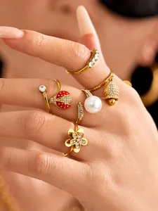 Detailed close-up of gold-plated rings featuring ladybug, pearl, and bell charms