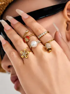 Macro detail of gold-plated rings set featuring ladybug, pearl, and bell designs