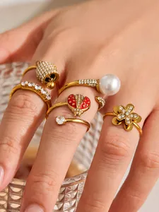 Close-up detail of gold-tone zircon rings featuring ladybug, bell, and flower motifs