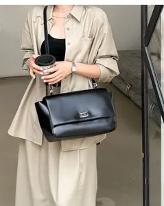 Elegant black leather flap shoulder bag with a metal lock shown in a lifestyle context