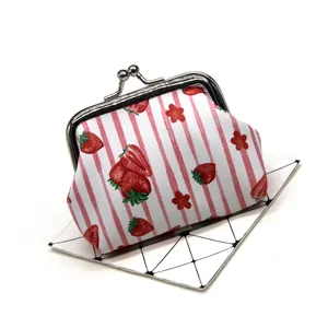 Detail showing the strawberry pattern and metal kiss-lock clasp of the coin purse