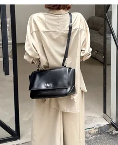 Back view of a black genuine leather messenger bag with flap and metal clasp