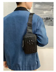 Homme portant un sac de poitrine en cuir noir à motif crocodile et veste en jean.