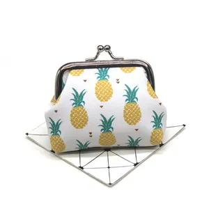 Close-up detail of a small white coin purse with vibrant pineapple print and metal clasp