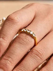Macro detail view of an elegant gold-plated ring set with five brilliant white zircons.