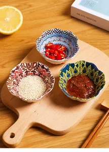 Three Japanese ceramic sauce bowls with colorful patterns on a rustic wooden board